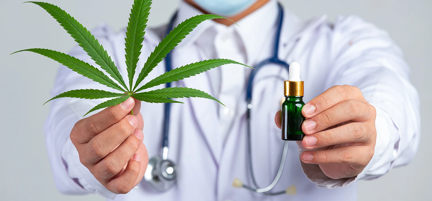 Homme avec une blouse qui tient un flacon de CBD et une feuille de CBD